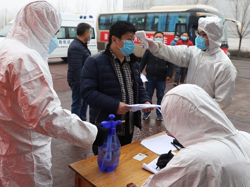 A migrant worker has his temperature taken on Feb. 25 after arriving on a chartered "point-to-point" bus from Henan, at a factory in Zouping, in China's Shandong province